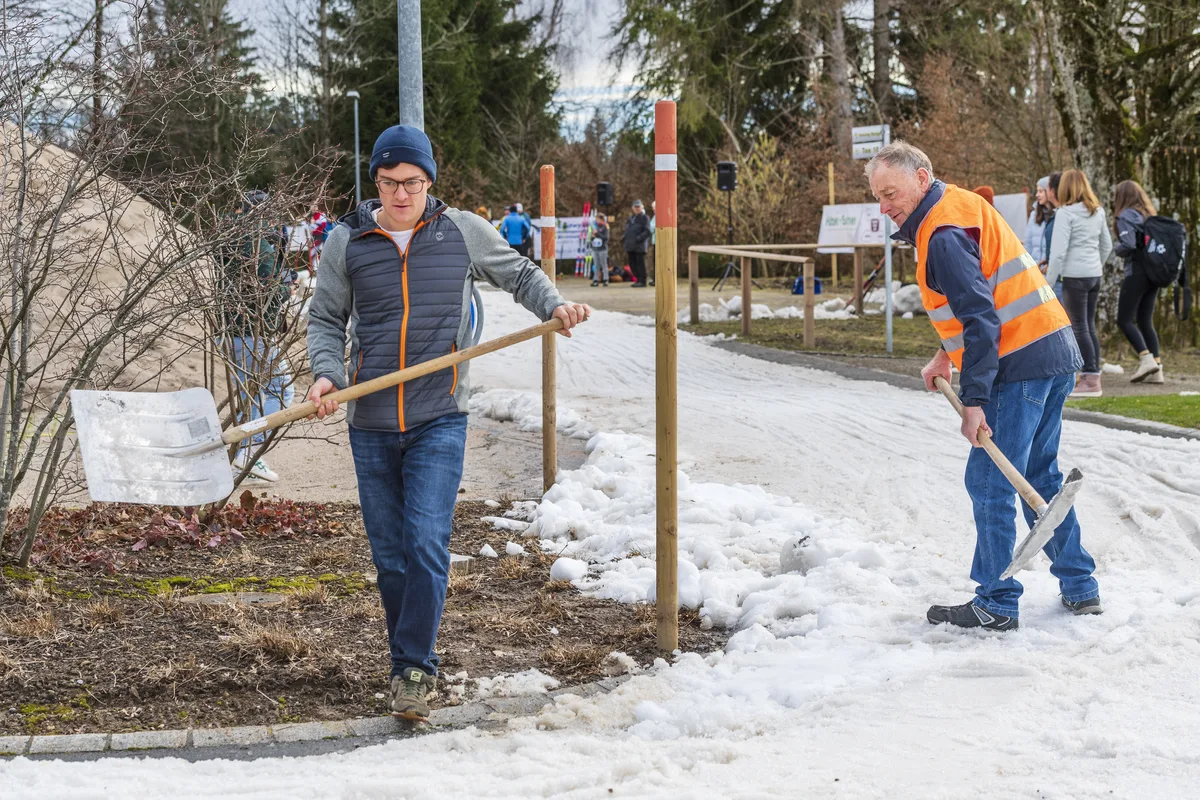 Zwei Männer mit Schaufeln präparieren eine Loipe.